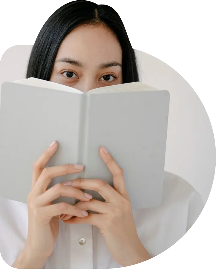 Mulher segurando um livro aberto à frente do rosto.